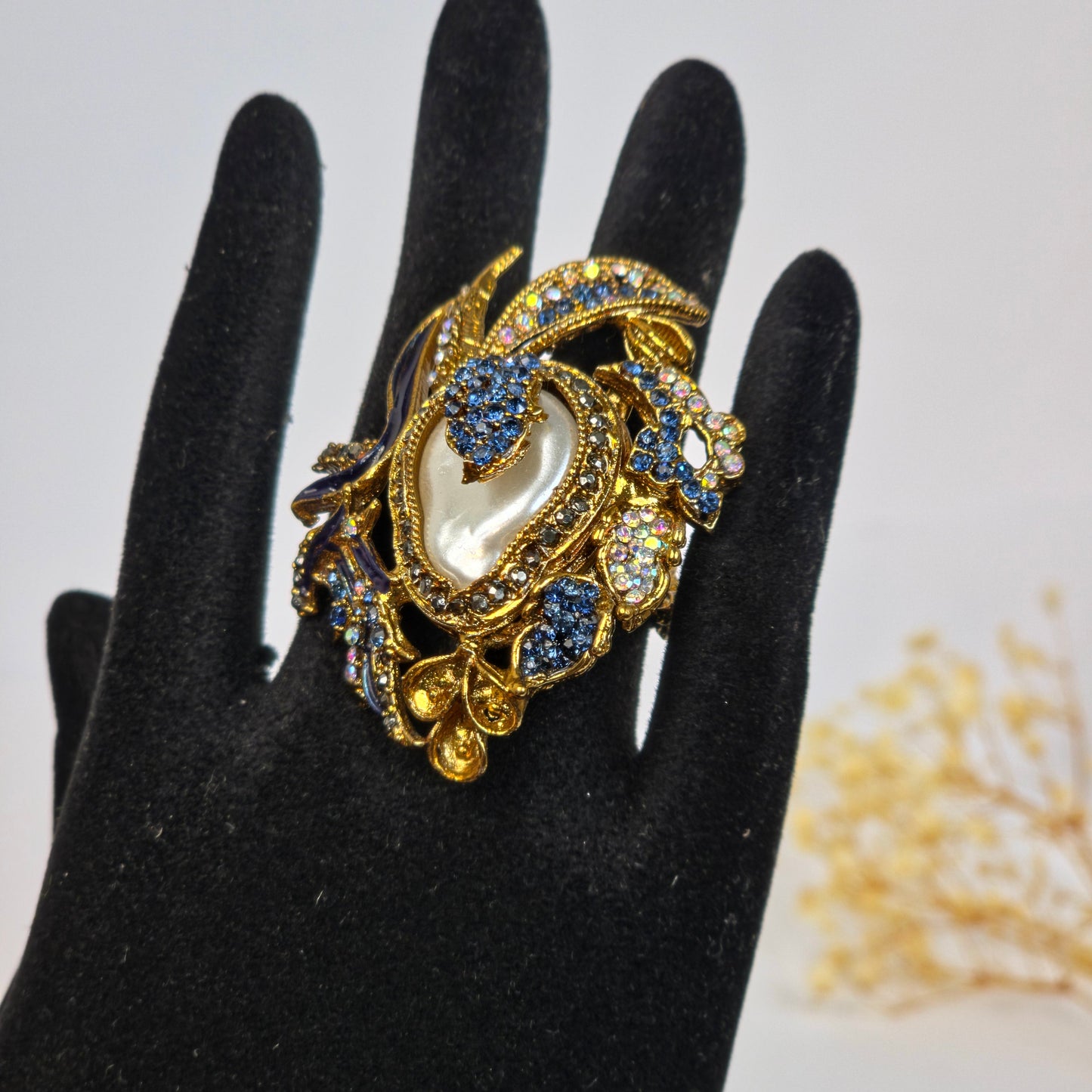 Decorative brooch with pearls and gemstones on a black glove
