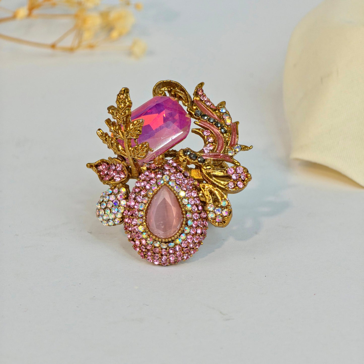 Decorative brooch with pink gemstones and gold accents on a light gray background