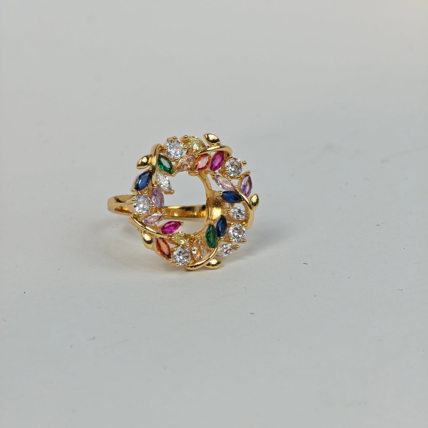 Gold ring with colorful gemstones on a light gray background