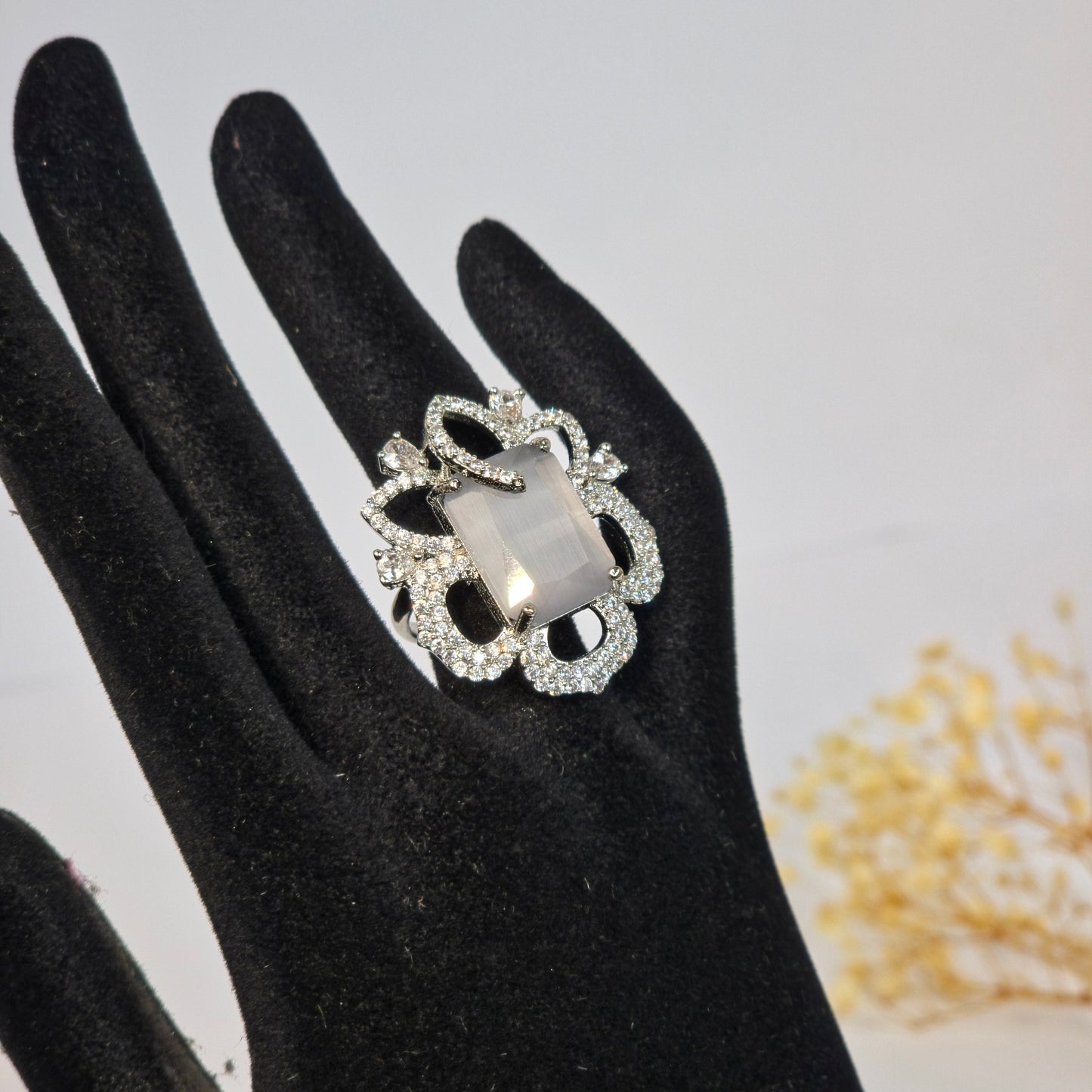Decorative ring on a black-handled glove against a neutral background
