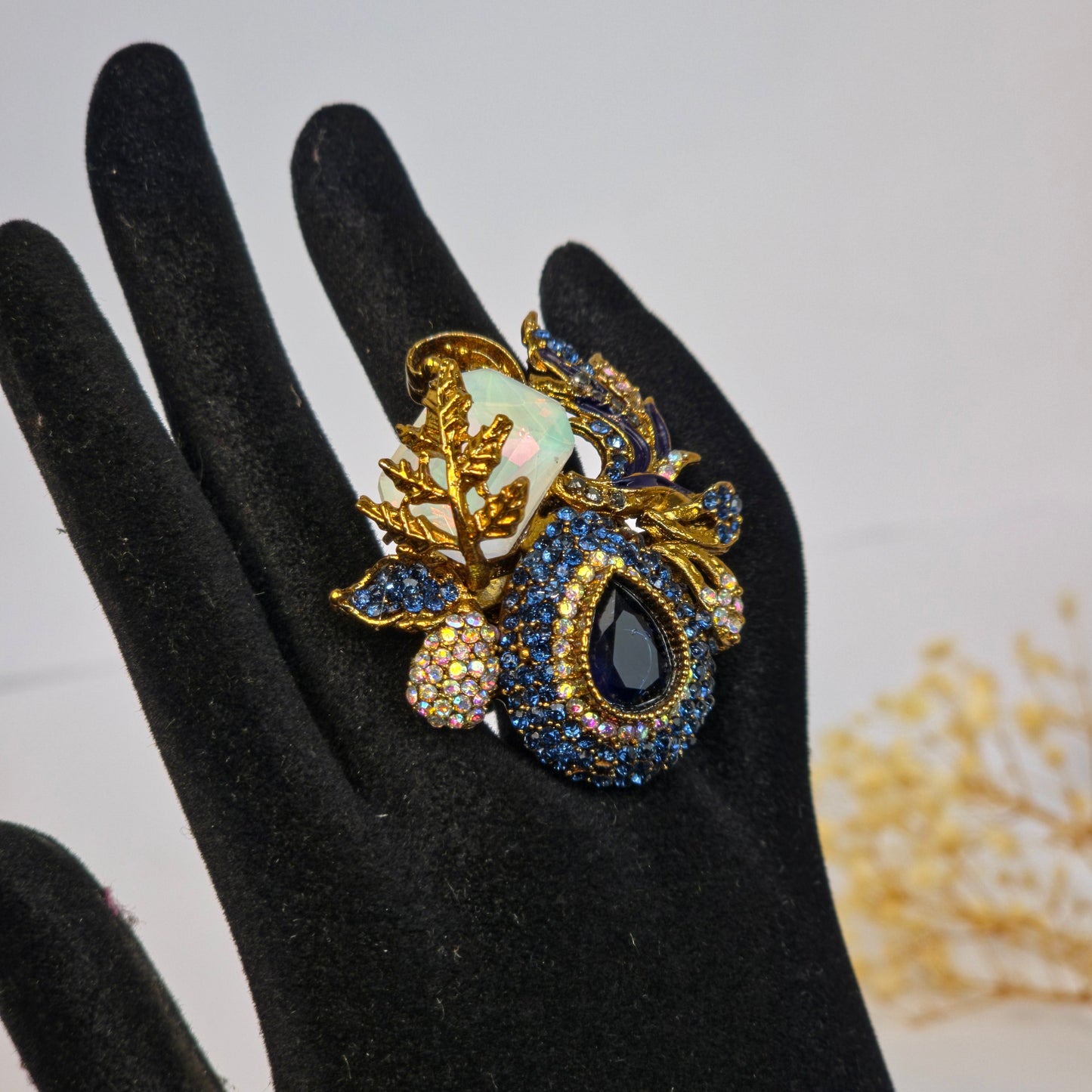 Decorative ring with gemstones on a black glove against a light background