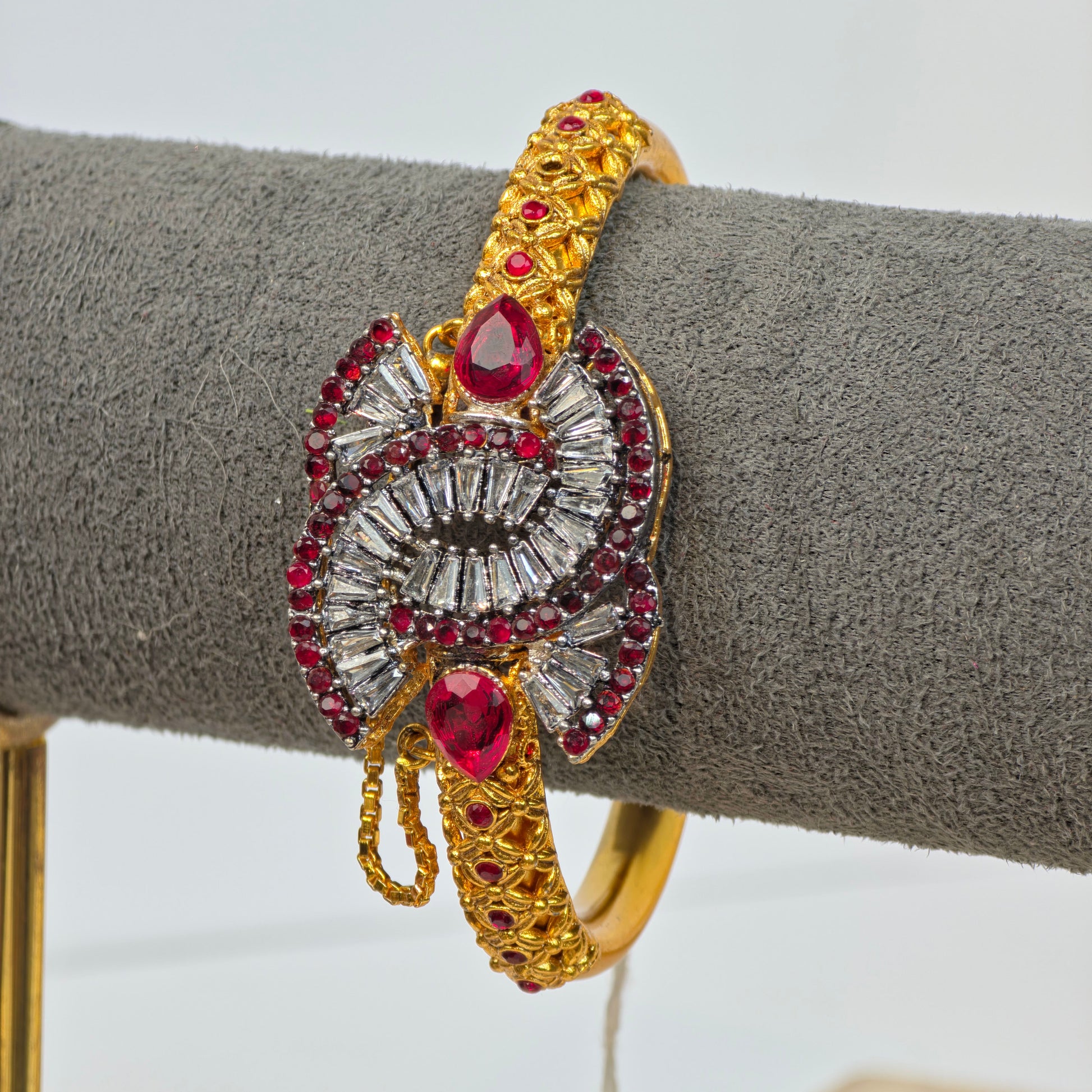 Antique gold-plated Pakistani kara with maroon teardrop stones and white zircon baguette crystals on a traditional filigree patterned base.