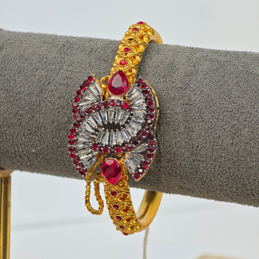 Antique gold-plated Pakistani kara with maroon teardrop stones and white zircon baguette crystals on a traditional filigree patterned base.