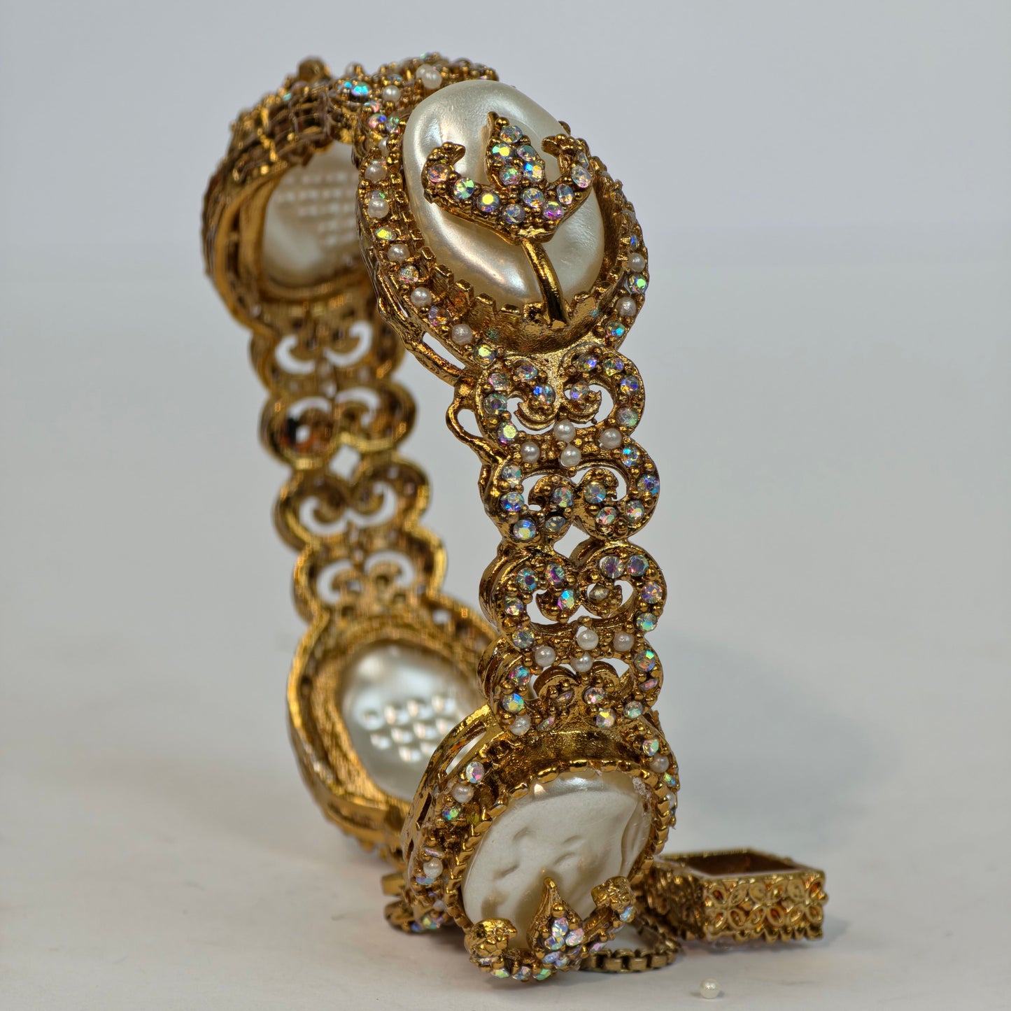 Gold bracelet with pearls and crystals on a white background