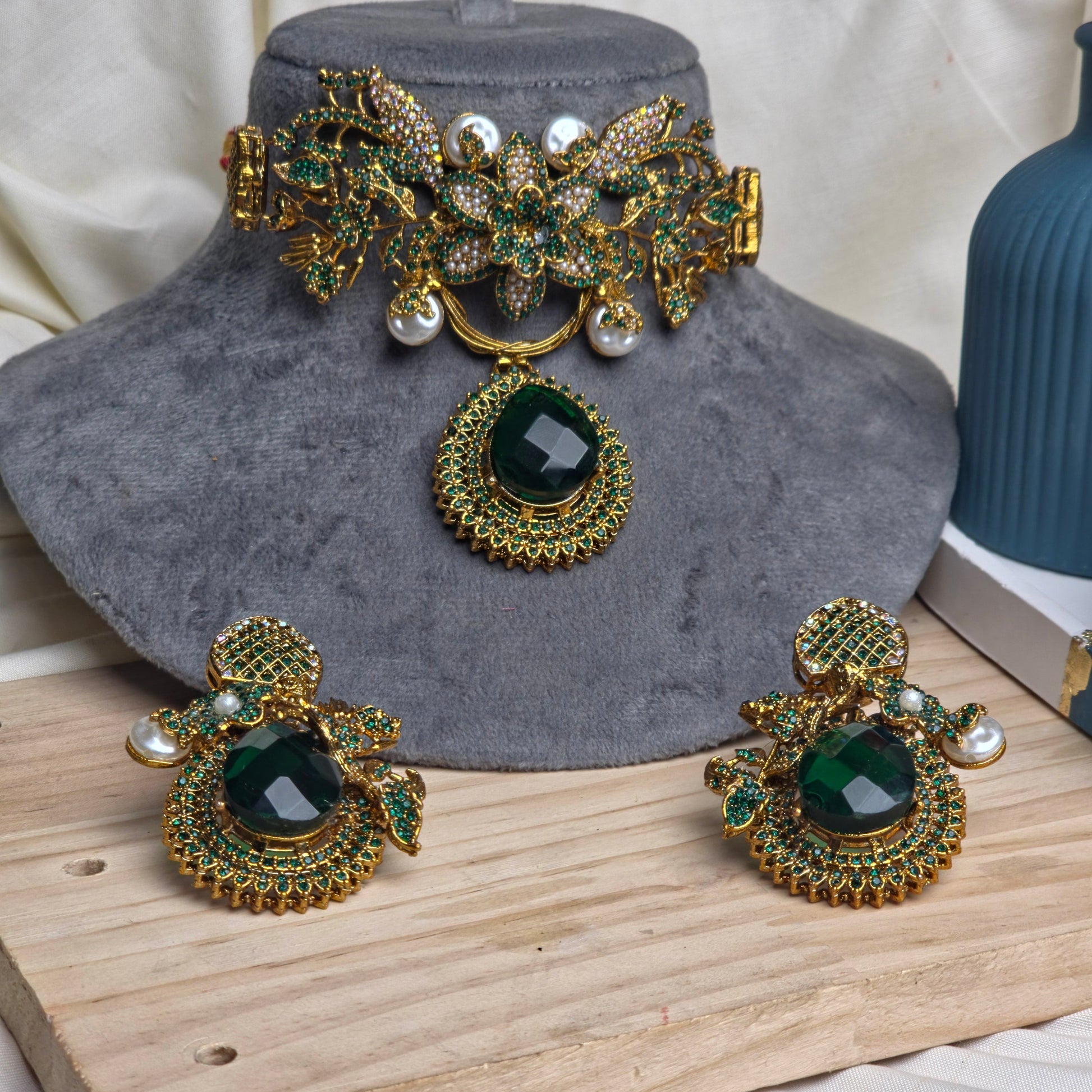 Ornate gold and green earrings on a textured surface