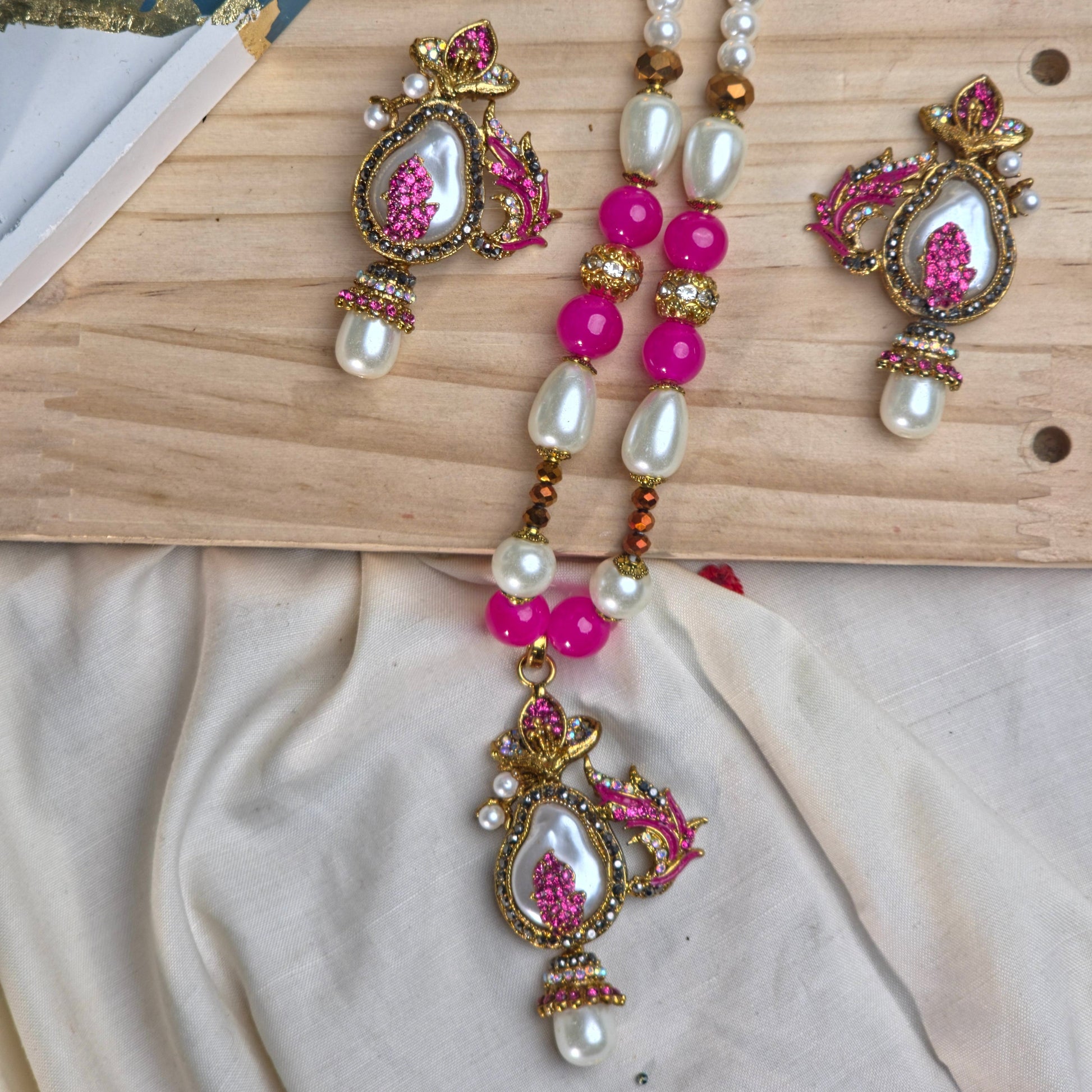 Decorative necklace with pink and gold elements on a wooden surface