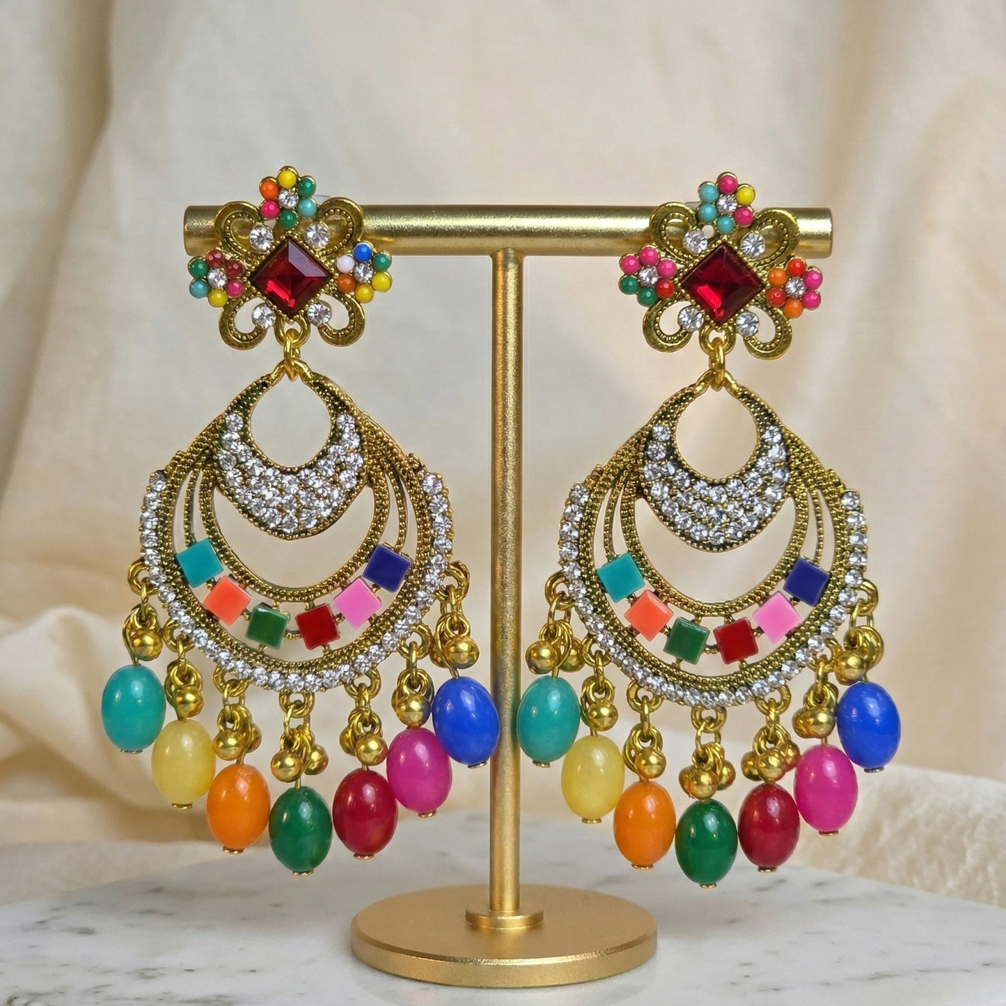 Colorful earrings on a gold stand with a neutral background