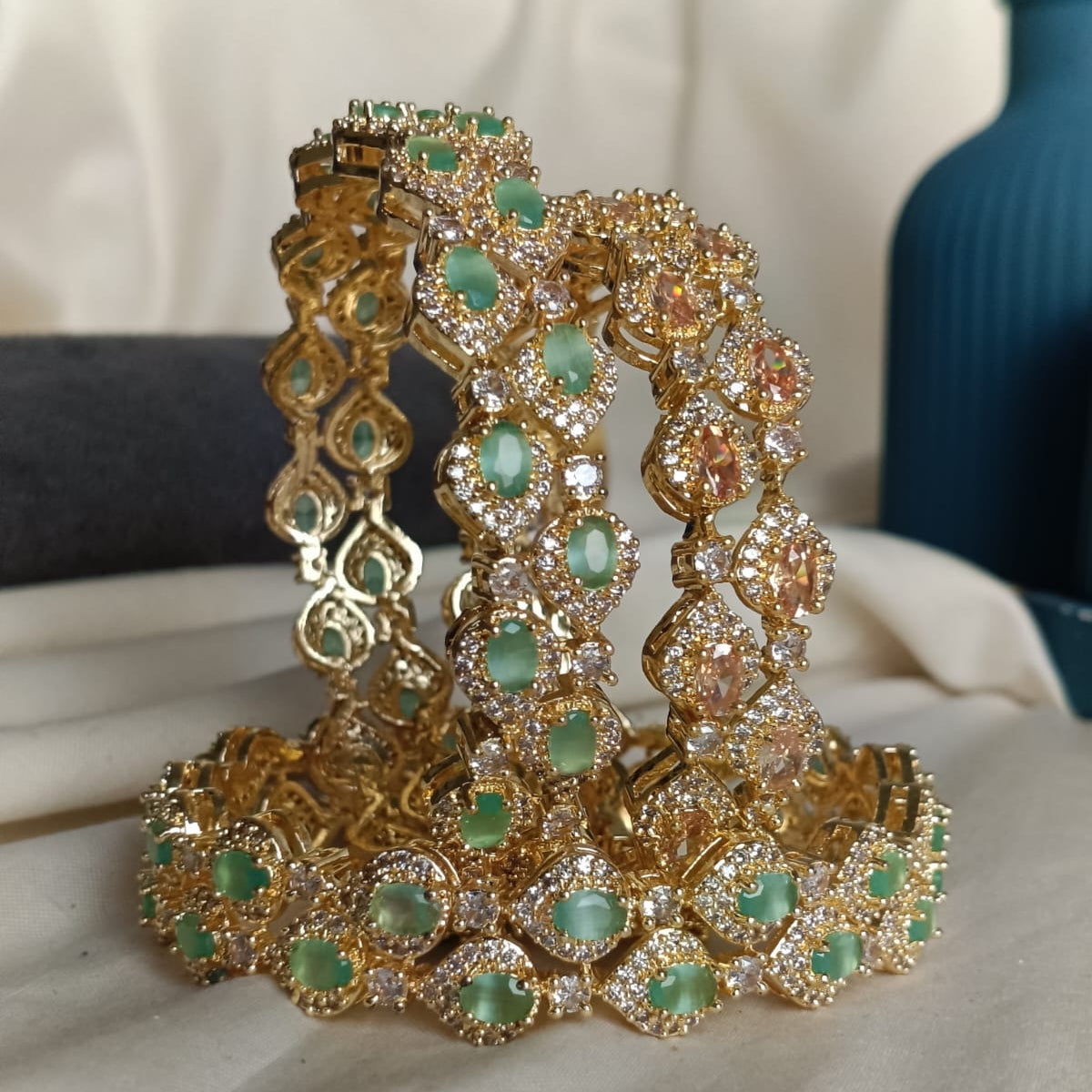 Gold bracelet with green gemstones on a white surface