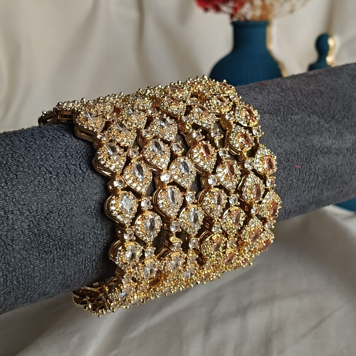Gold bracelet with intricate design on a gray surface, blurred background