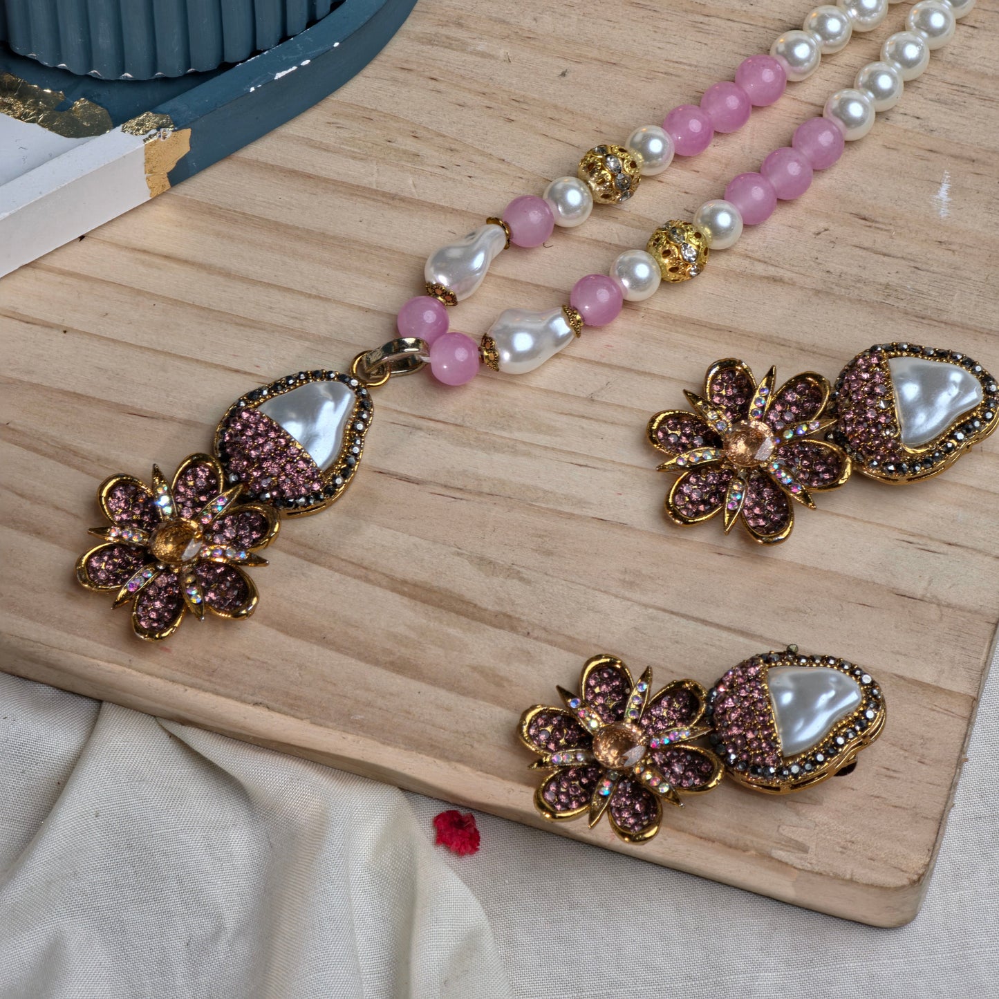 Pearl and gemstone necklace with matching earrings on a wooden surface.