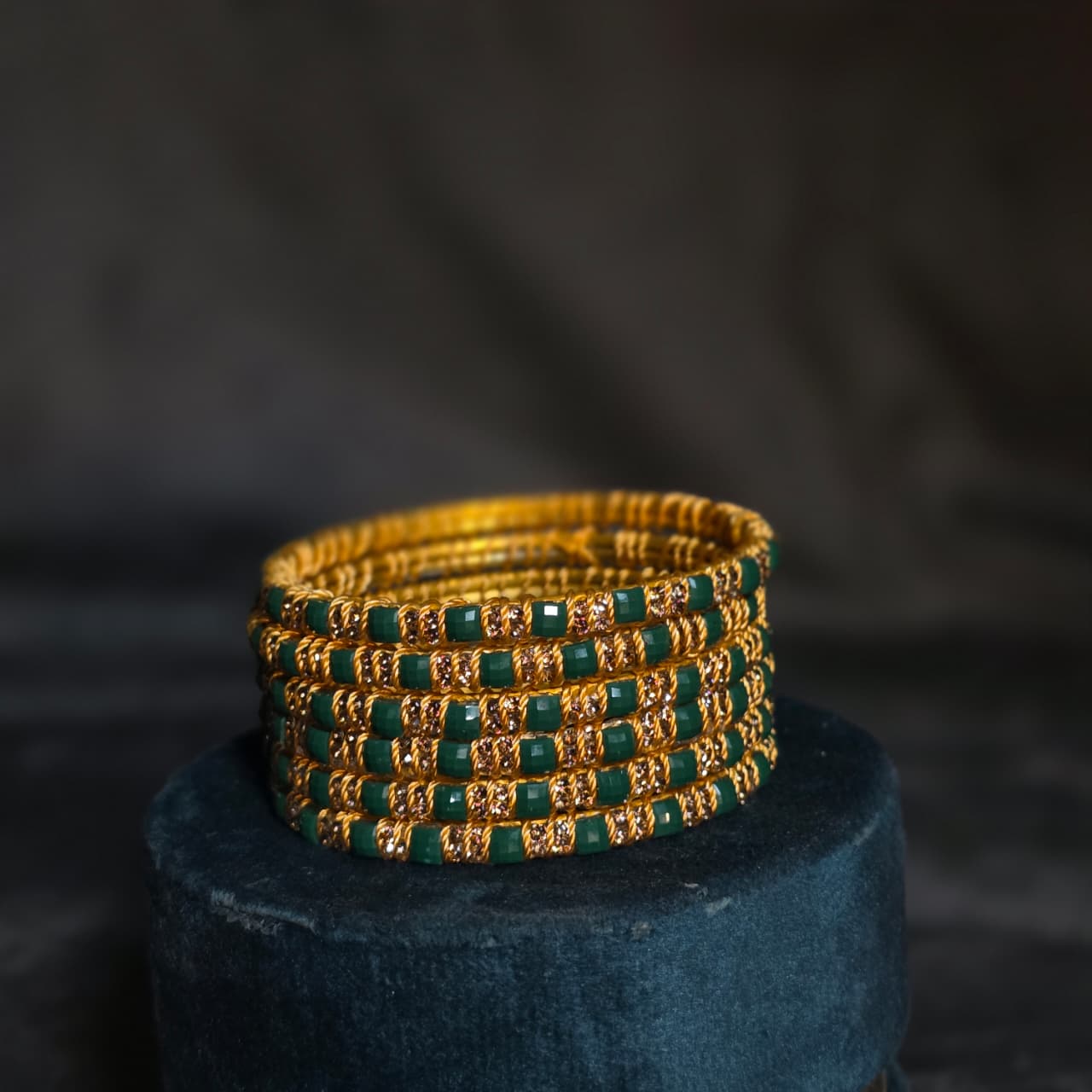 "Multicolor set of square-cut stone bangles with gold wire detailing on a wooden stand – Choori Wala by De Fleuristes."